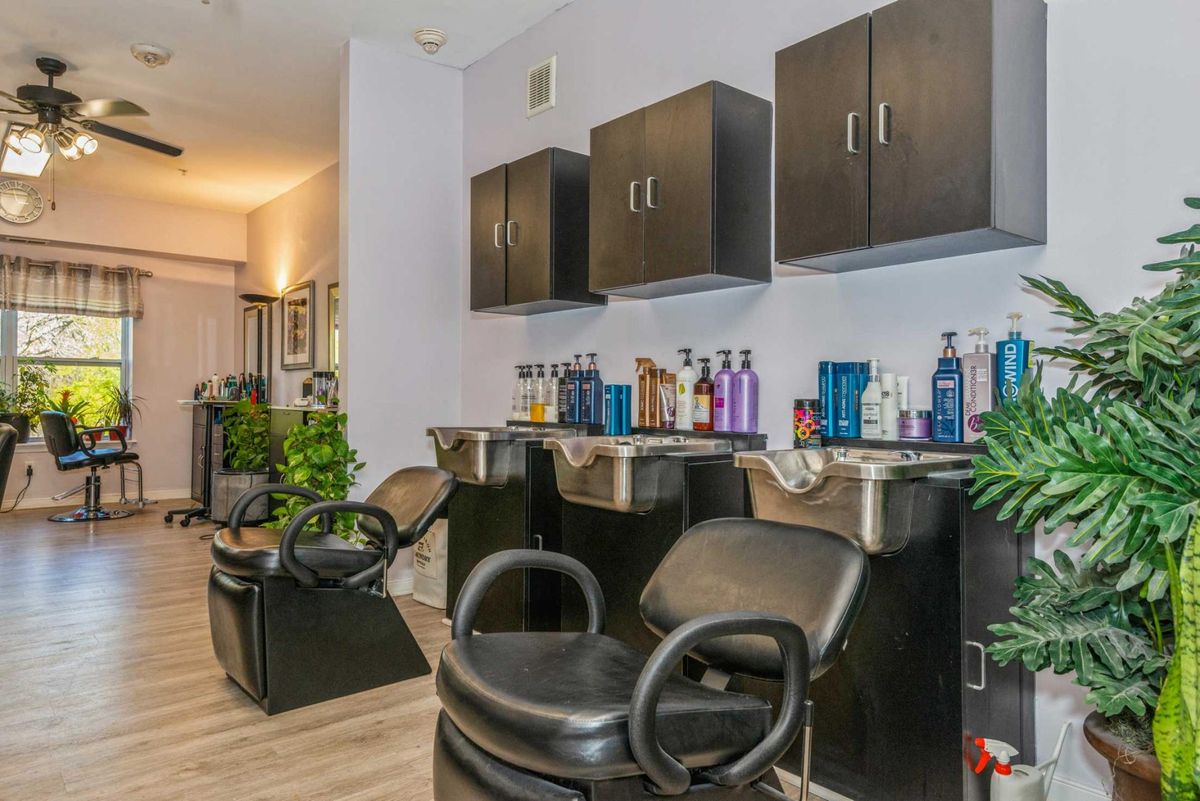 Interior of a modern hair salon with styling chairs and washbasins.