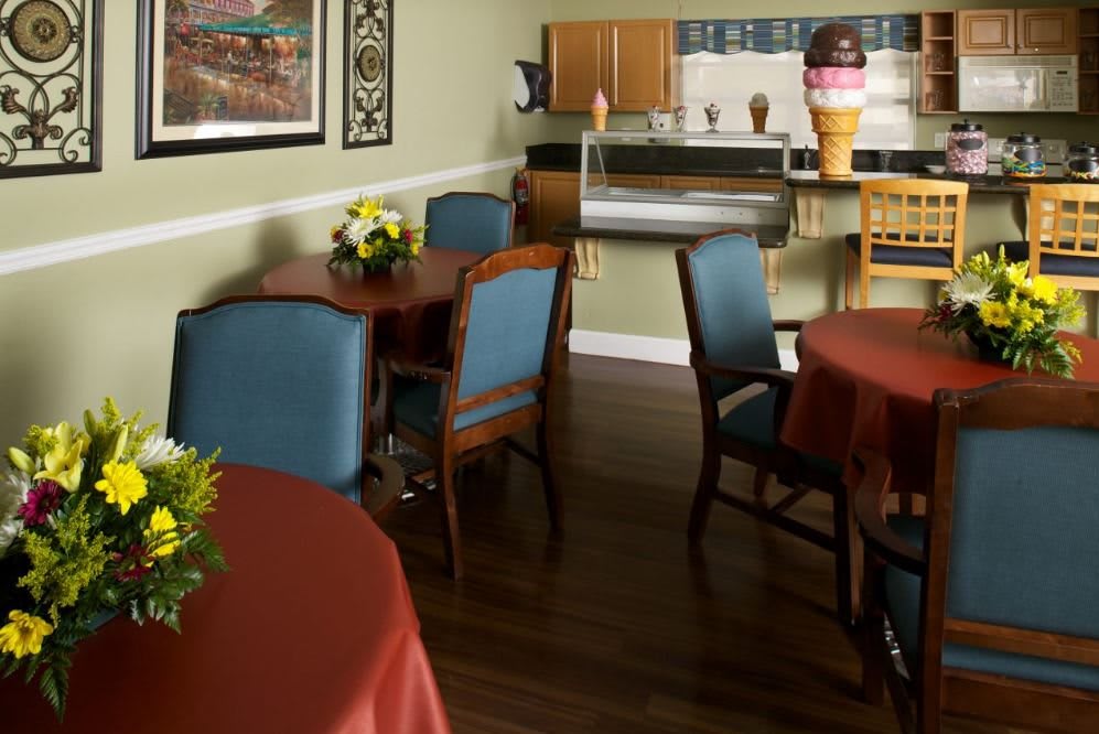 A cozy cafe interior with tables and chairs, featuring decorative flowers and ice cream-themed decor.