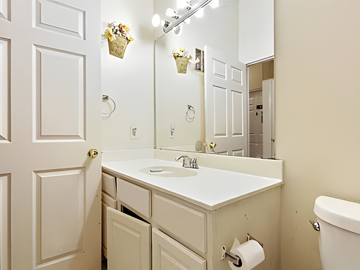A clean and bright bathroom with a sink, mirror, and cabinets.