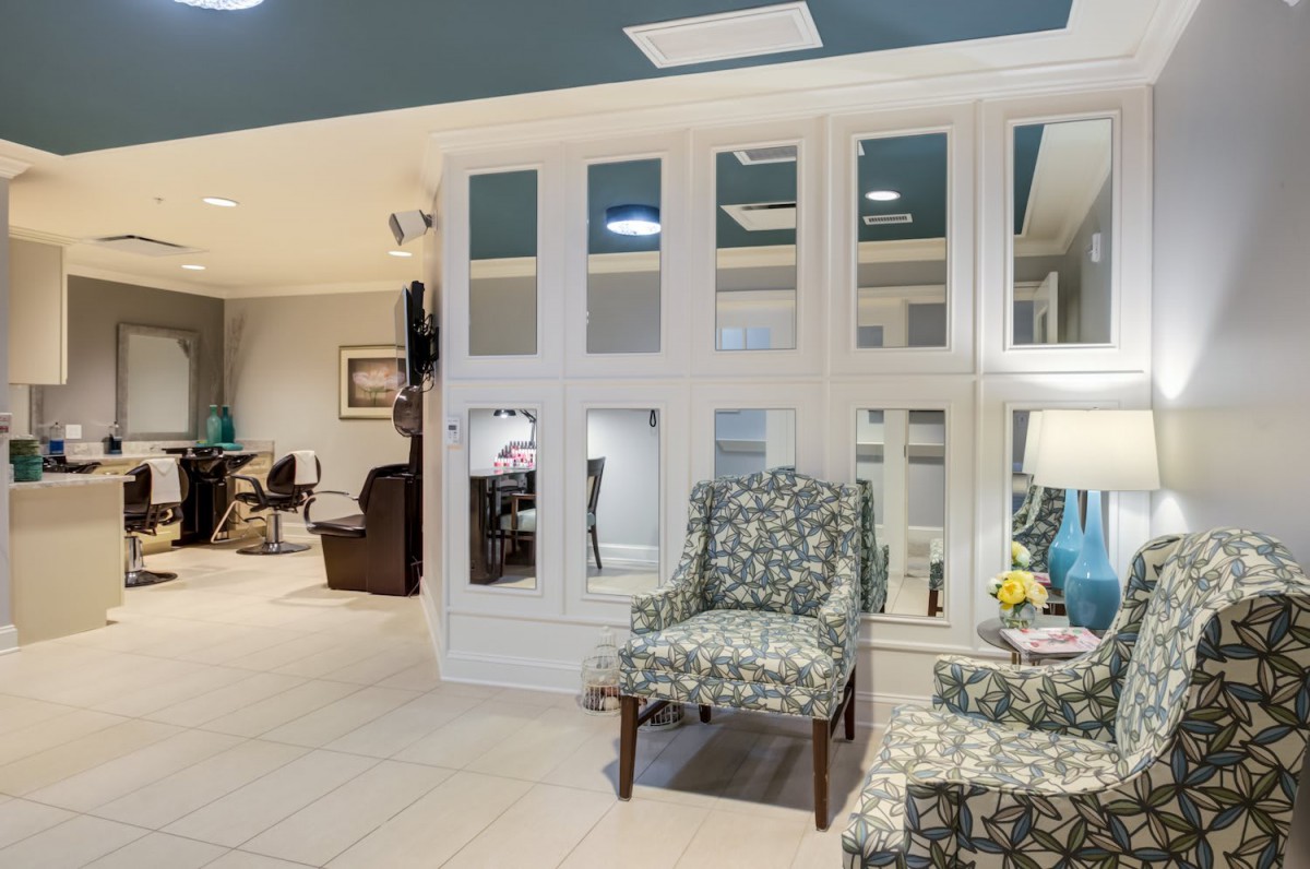A cozy seating area featuring patterned chairs and a large mirrored wall.