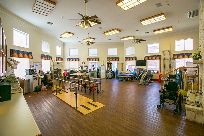A spacious rehabilitation center equipped with various physical therapy tools and exercise equipment.