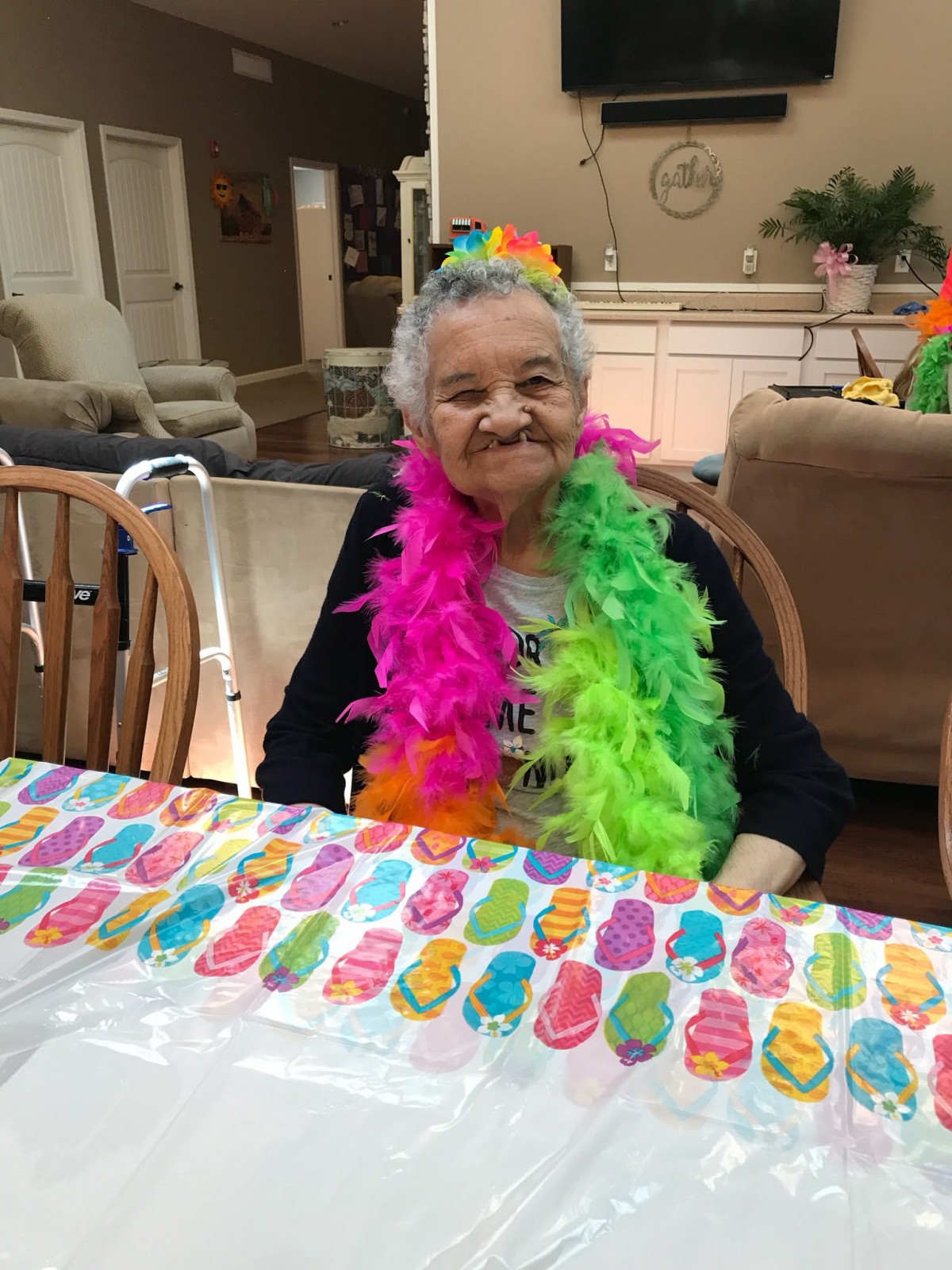 An elderly person enjoying a festive birthday celebration with colorful decorations and a feather boa.