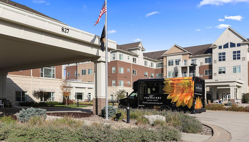 A delivery truck parked outside a residential or commercial building with an American flag flying nearby.