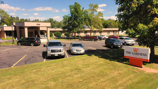 A view of a parking lot with various cars and a landscaped area featuring trees.