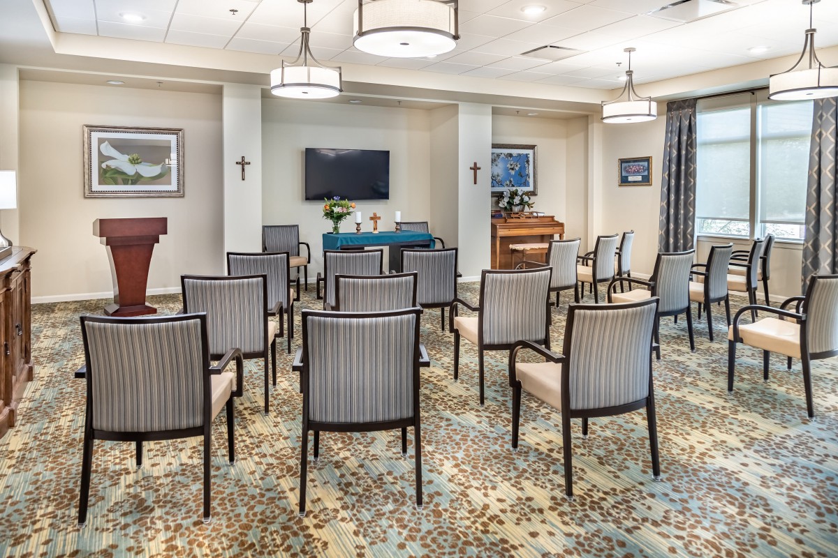 A modern conference room with neatly arranged chairs facing a podium and screen.