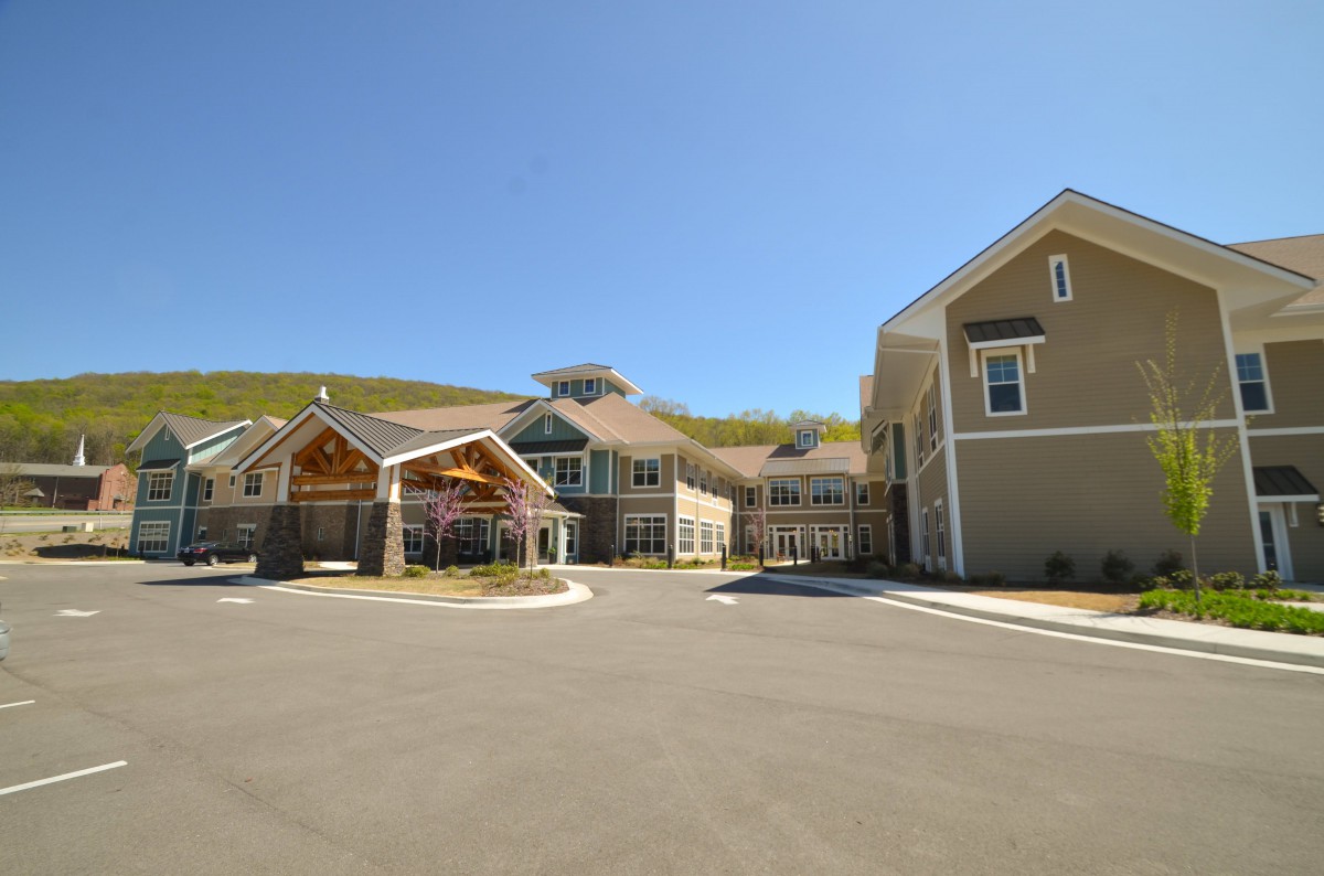 A modern building with a spacious entrance and driveway on a sunny day.