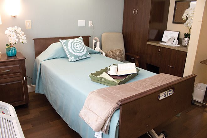A clean and organized hospital room with a neatly made bed.