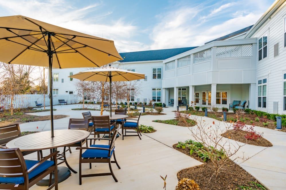 A well-maintained outdoor patio area with seating arrangements and umbrellas, located beside a building.
