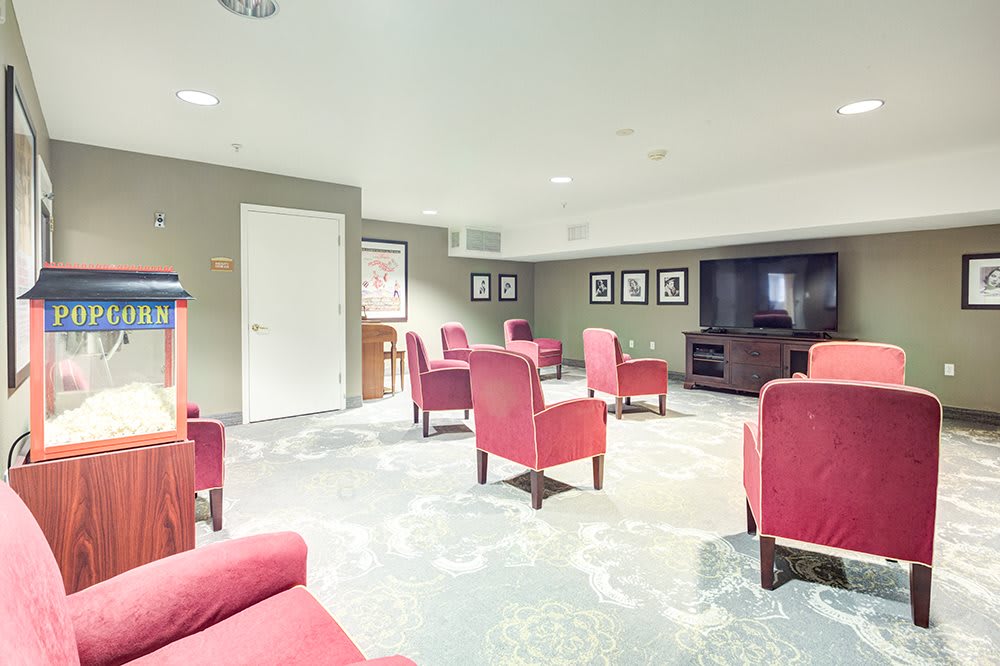 A cozy entertainment room with red chairs and a large television.