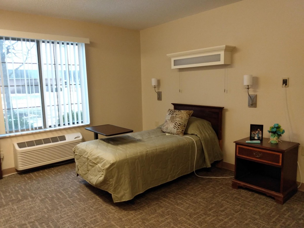 A simple and tidy bedroom with a single bed and a window letting in natural light.