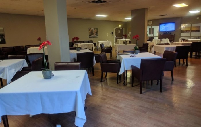 An empty restaurant dining area with tables covered in white tablecloths.