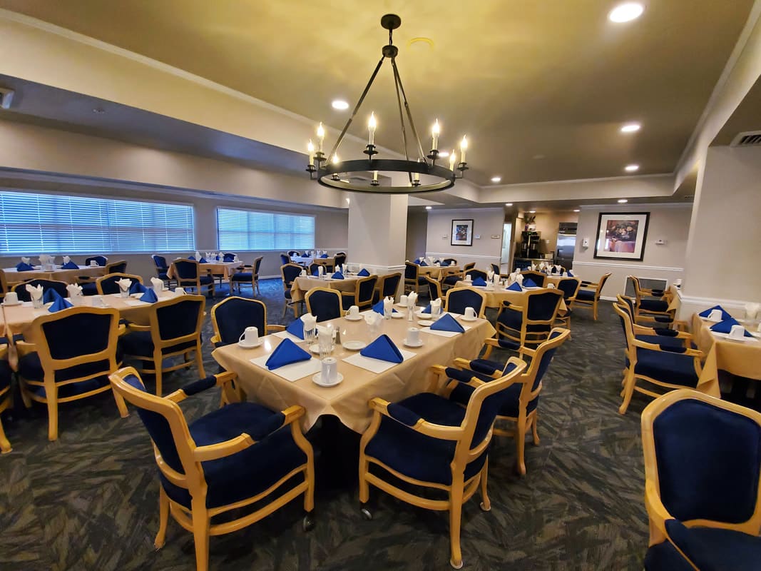 An elegantly set dining room with neatly arranged tables and a central chandelier.