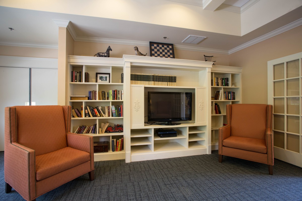 A cozy living room with a bookshelf, television, and comfortable chairs.