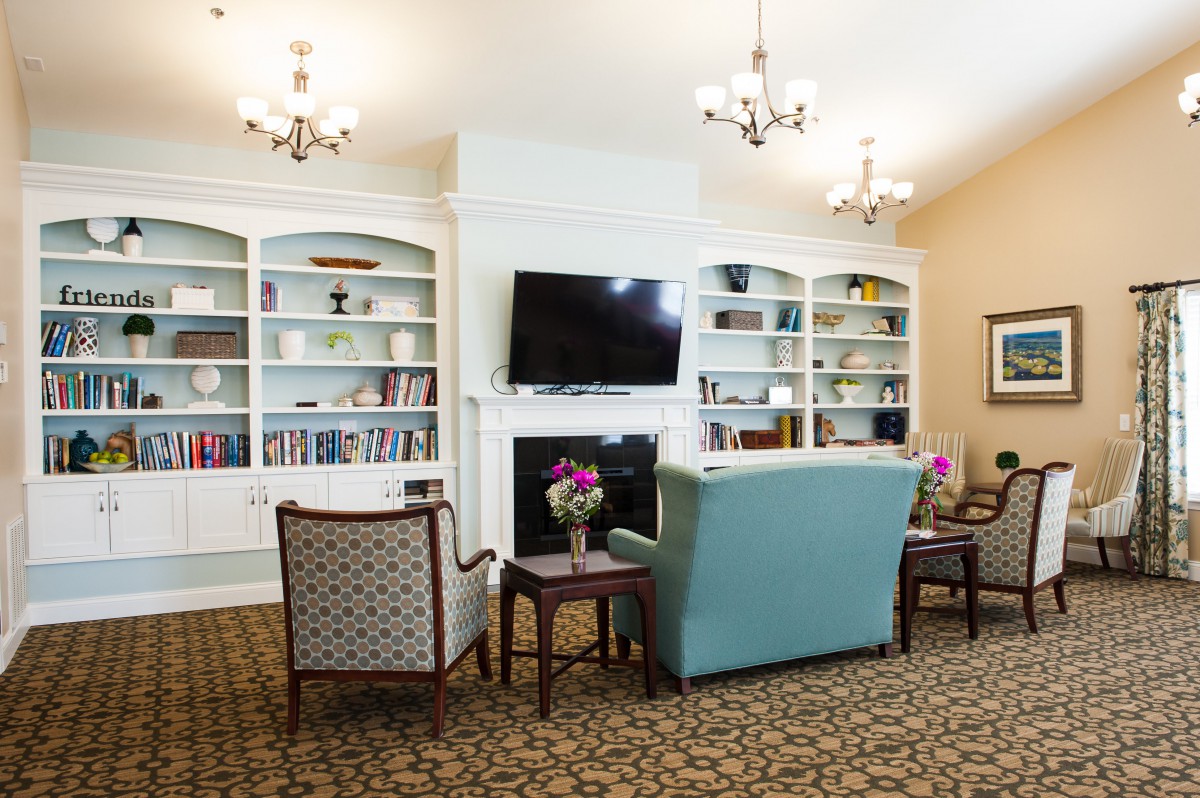 A cozy living room with a seating area, bookshelves, and a television.