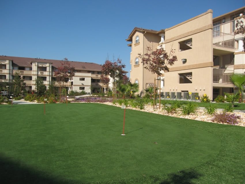 A view of apartment buildings with a well-maintained lawn on a sunny day.