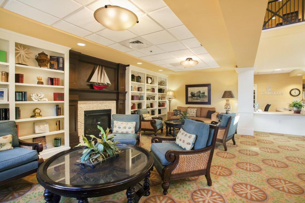 A cozy living room with comfortable chairs, a fireplace, and bookshelves filled with books.