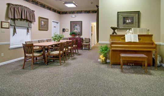 A room with chairs and tables, a piano, and decorative elements on the walls.