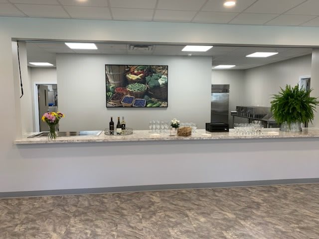 A modern reception area with a counter, featuring flowers and artwork.