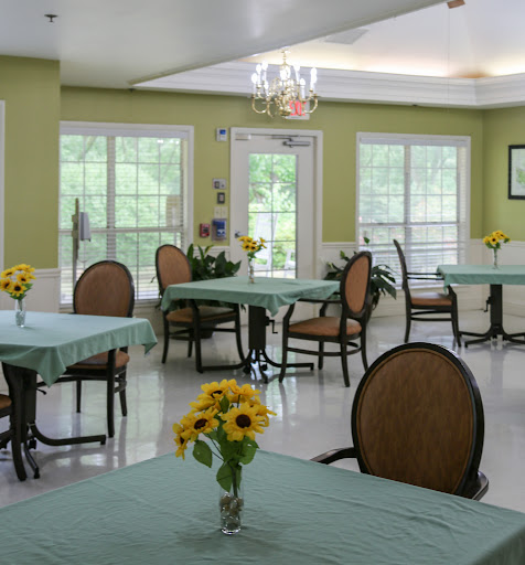 A bright and inviting dining area featuring tables set with flower arrangements, surrounded by large windows.