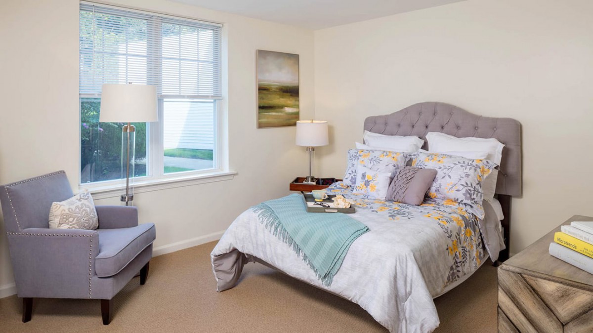 A cozy and well-decorated bedroom with a plush bed, soft lighting, and a large window.