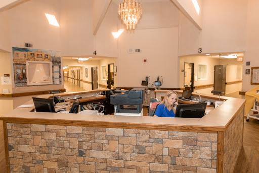 A modern reception area featuring a stylish chandelier and a dedicated staff member at the front desk.