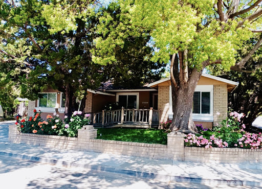 A charming residential house surrounded by lush greenery and vibrant flowers.