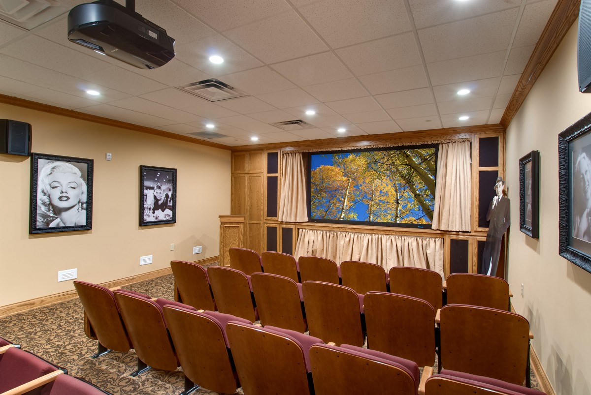 A cozy home theater with a large screen, comfortable seating, and a ceiling-mounted projector.