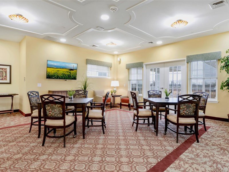 A cozy dining area with multiple tables and chairs, adorned with a patterned carpet and bright lighting.