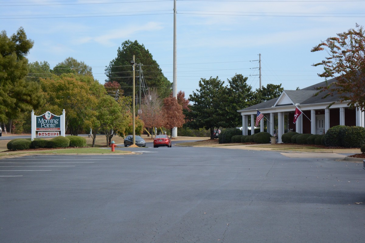 A quiet suburban street lined with trees and buildings.