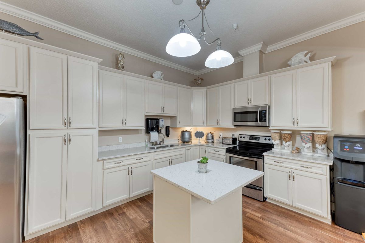 A modern kitchen with white cabinets, a central island, and stainless steel appliances.