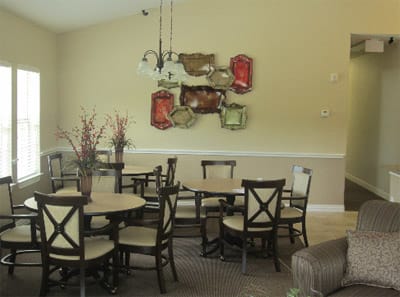 A dining area with multiple tables and chairs, decorated with wall art and hanging lights.