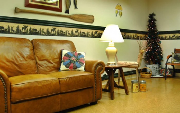 A cozy living room with a leather couch, decorative pillow, and warm lighting from a table lamp.