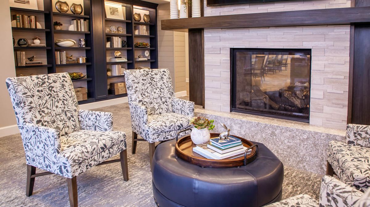 A cozy living room with armchairs, a fireplace, and bookshelves.