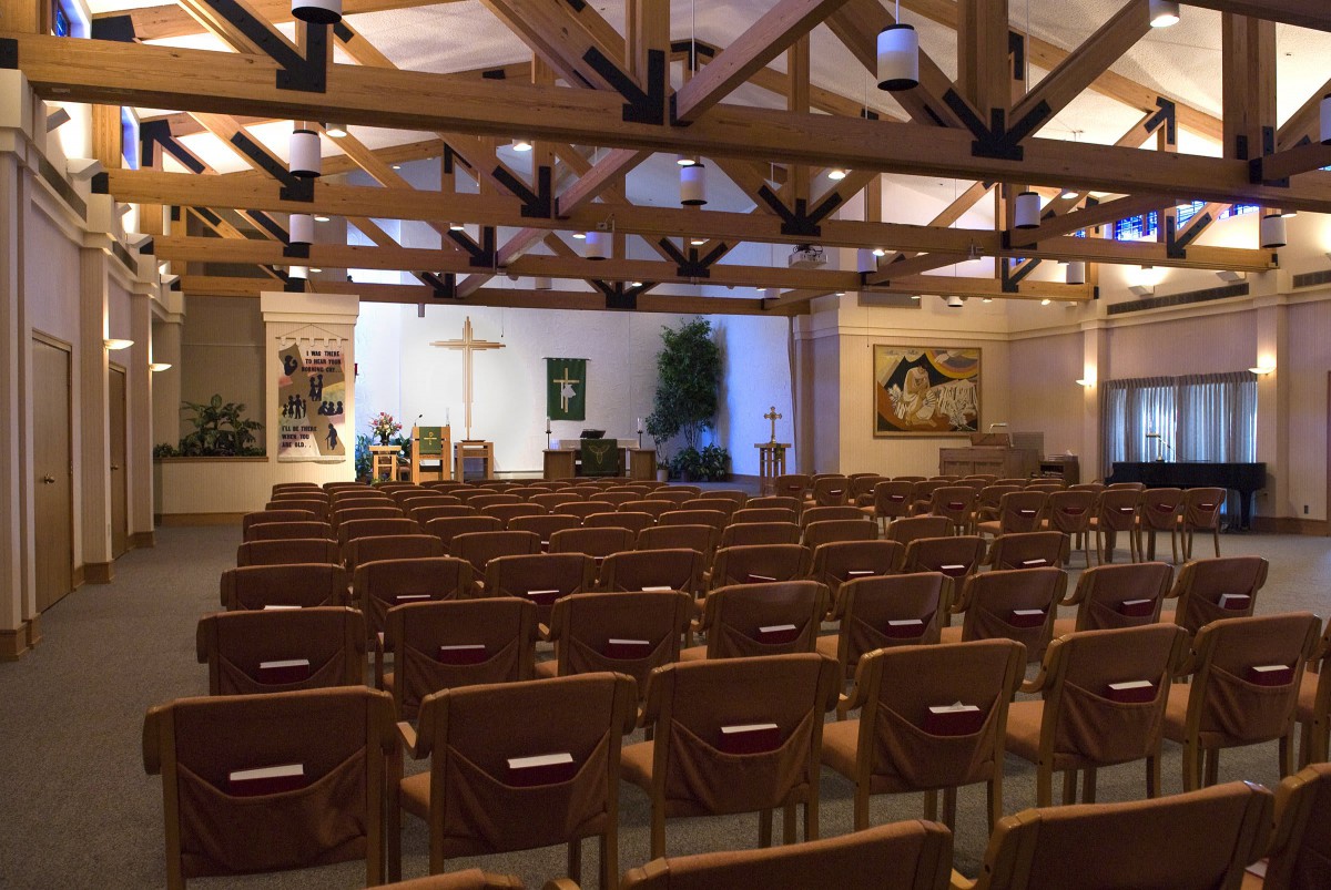 Interior view of a church with rows of chairs facing the altar and a cross.
