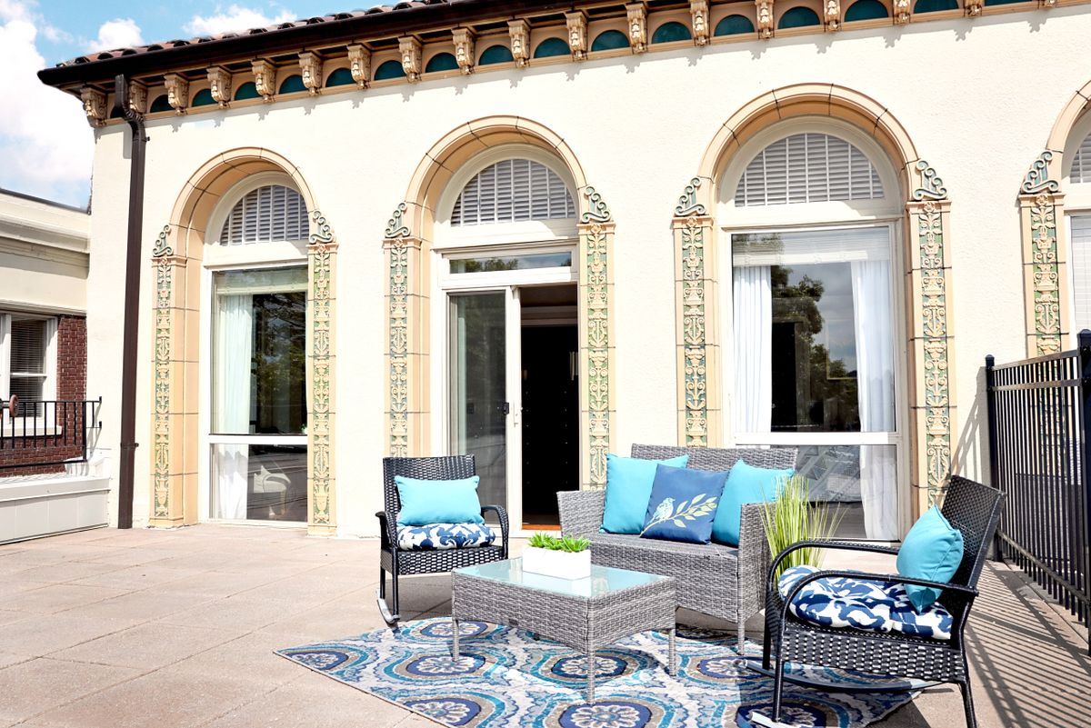 A stylish outdoor patio with modern furniture and decorative cushions set against an elegant building facade.