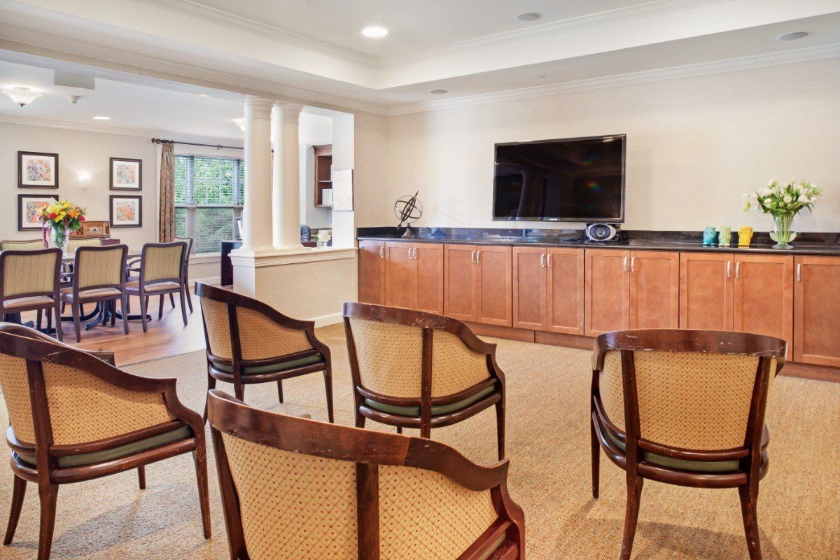 A modern conference room with wooden chairs and a large television.