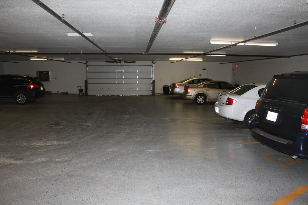 An indoor parking garage with several cars parked along the sides.