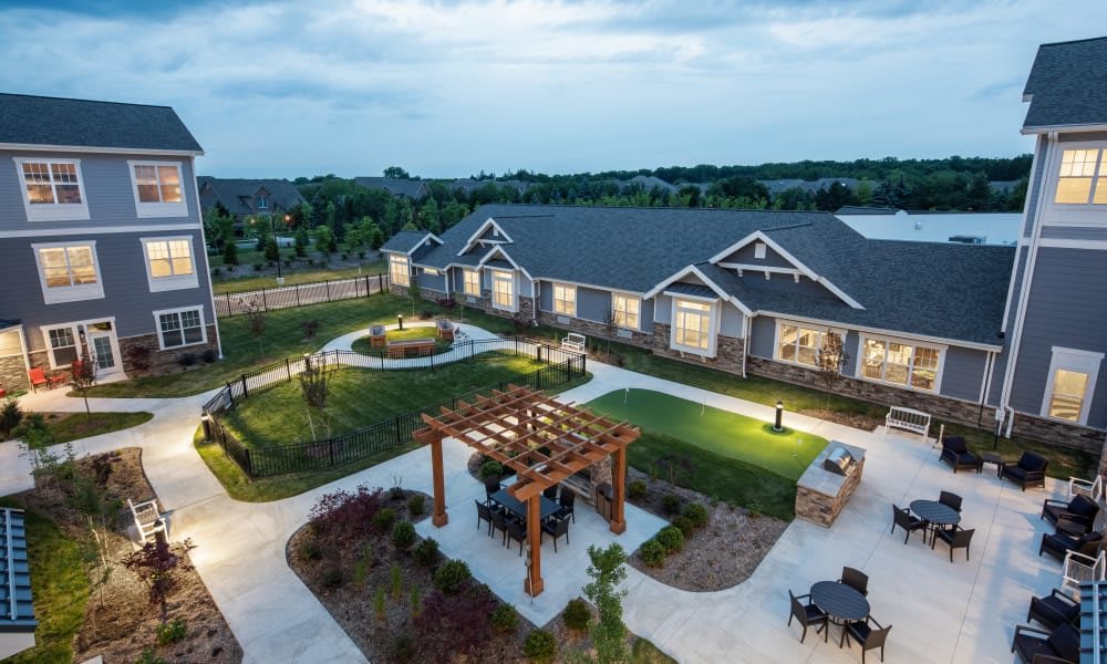 A picturesque view of a landscaped garden with a well-lit building and pergola during the evening.