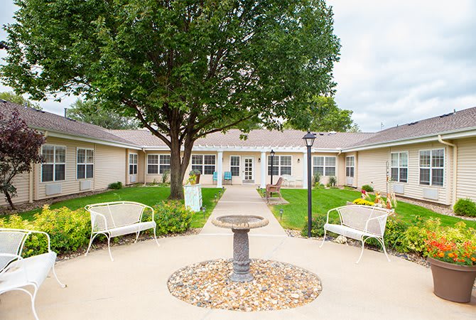 A serene courtyard with a circular pathway, benches, and a central fountain surrounded by greenery.