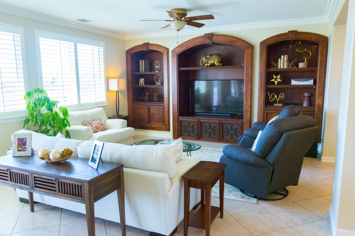 Spacious living room featuring a cozy sofa, armchairs, and built-in wooden shelving with a television.