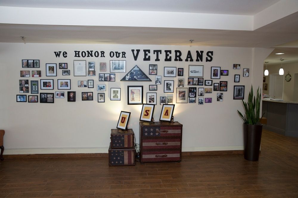 A tribute wall dedicated to veterans, featuring photographs, framed pictures, and American flag-themed decor.