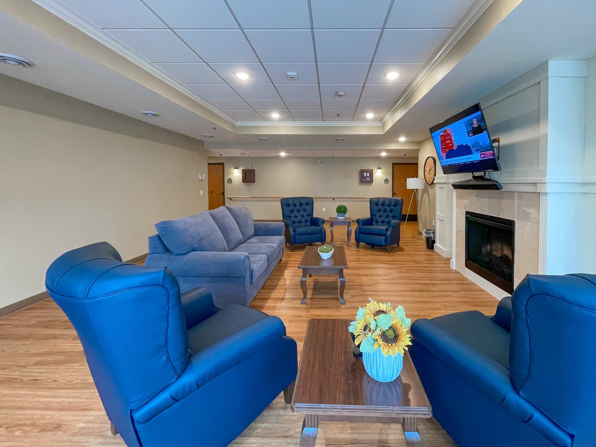 A cozy living room with blue furniture and a mounted television near the fireplace.