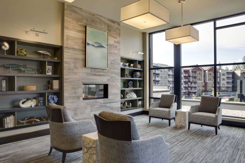 A modern living room with a cozy seating area around a fireplace, featuring contemporary furniture and decorative shelves.