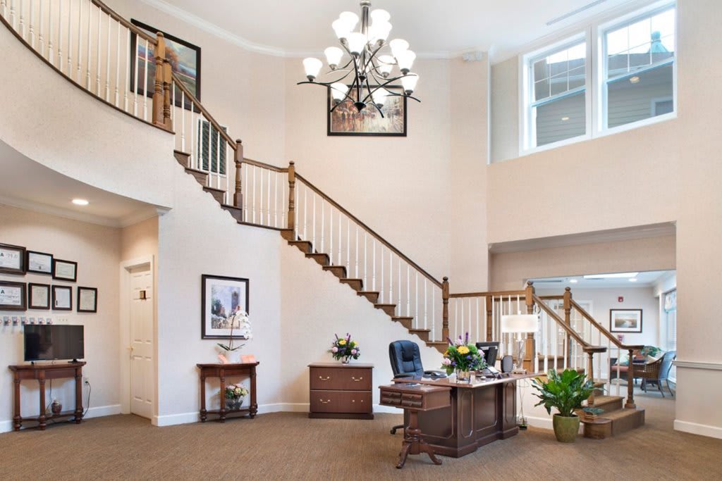 A spacious office interior with a desk, staircase, and chandelier.