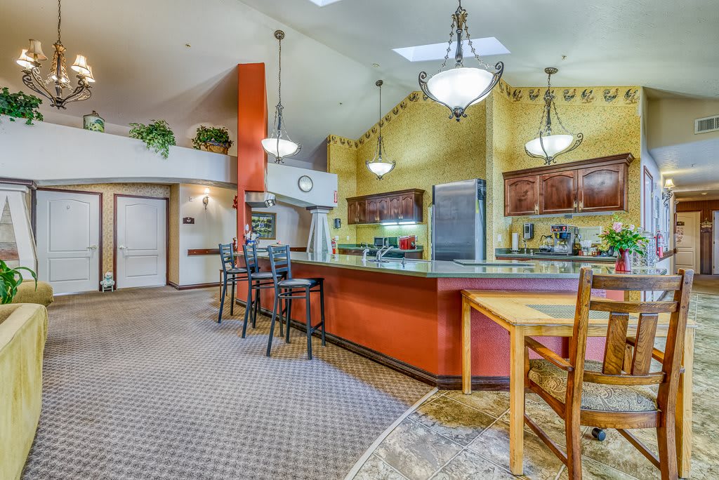 A spacious kitchen with a large counter, bar stools, and modern lighting.