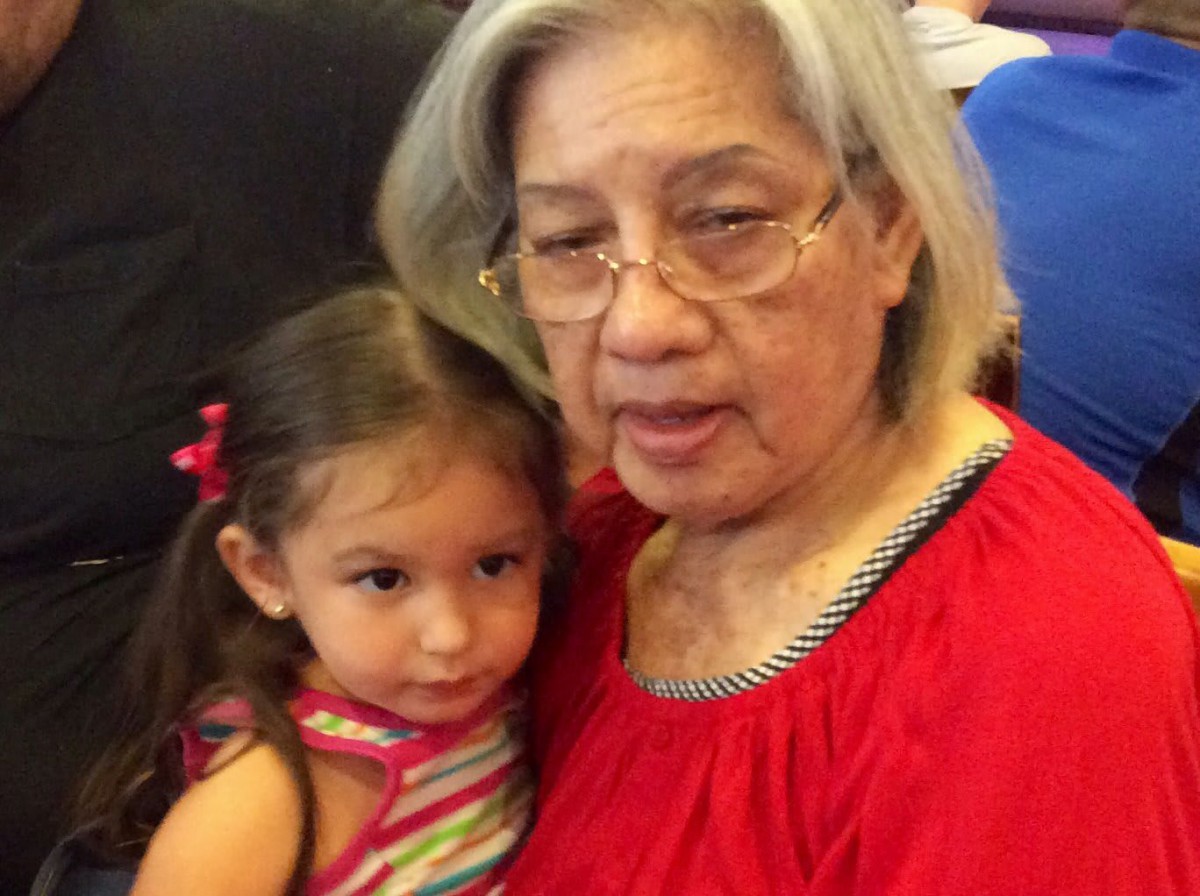 An elderly woman and a child cuddling together indoors.