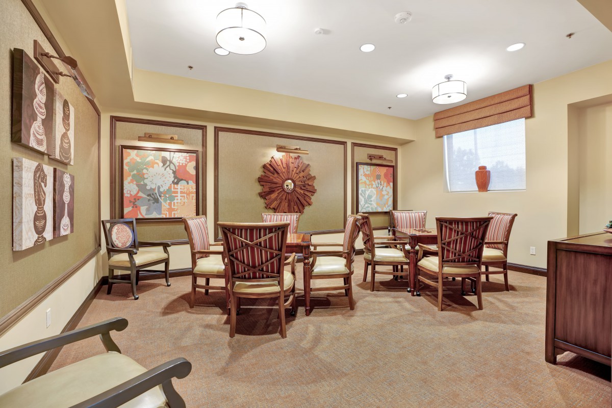 A well-furnished room with multiple chairs and tables, decorated with wall art and ambient lighting.