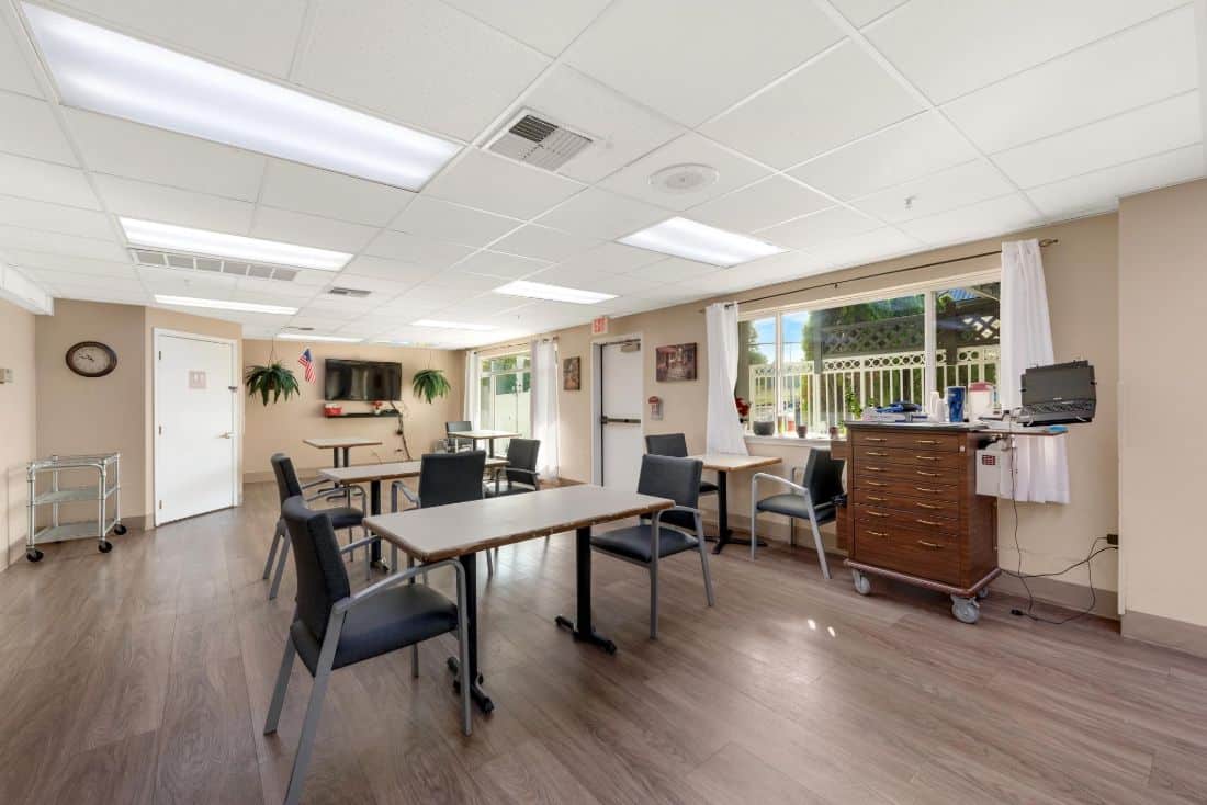 A bright and welcoming multipurpose room with tables, chairs, and large windows.
