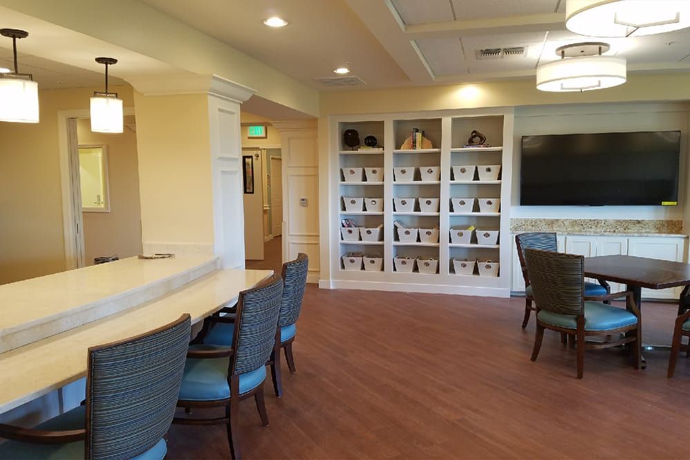 A cozy library with a large table, comfortable chairs, and shelves filled with books.