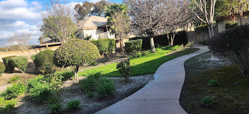 A serene view of a garden with a house in the background, featuring well-maintained greenery and a winding pathway.